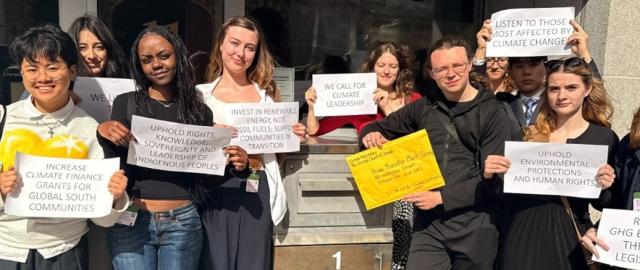 A group of youths hold up signs with slogans calling for climate leadership