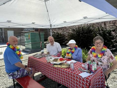 Four people sit around a picnic table with space left for more to join