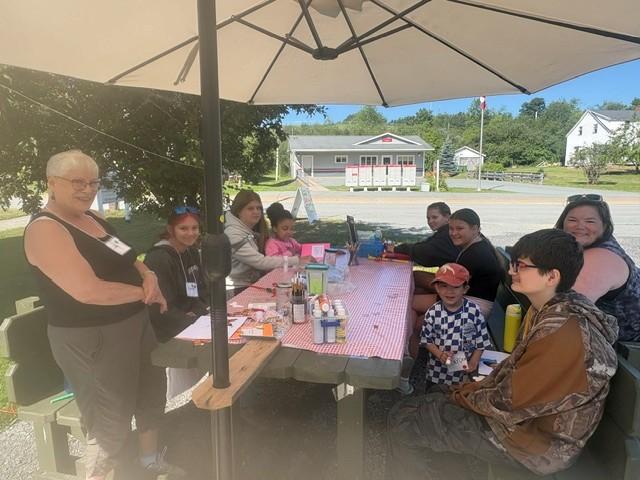 Children and adults sit around a picnic table