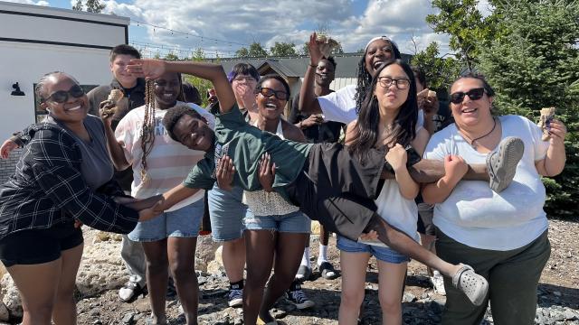 10 youth post for a photo energetically, with one being held across the middle by all