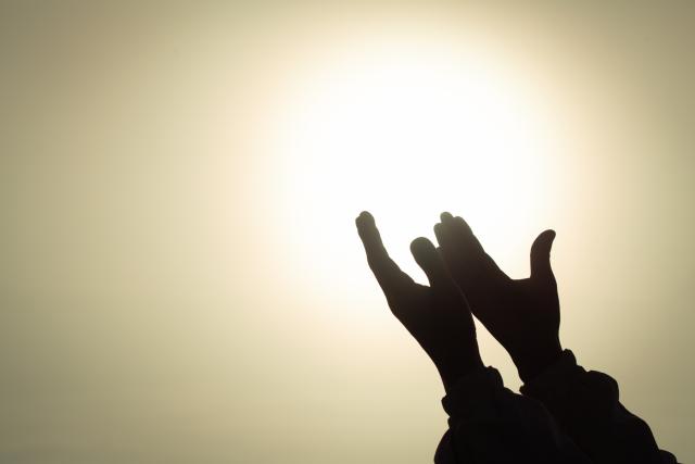 hands lifted in prayer toward light
