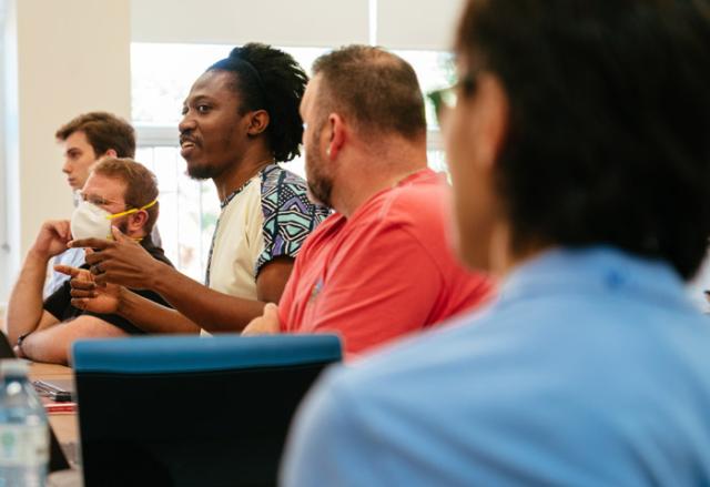 A person speaking in a room with other people.