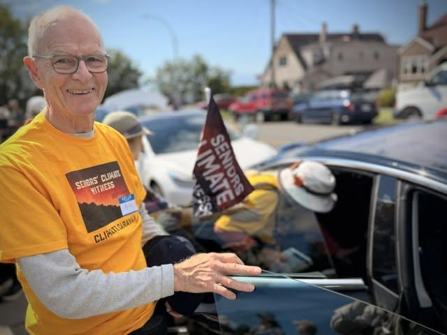 A smiling man in a yellow shirt gets out of a car
