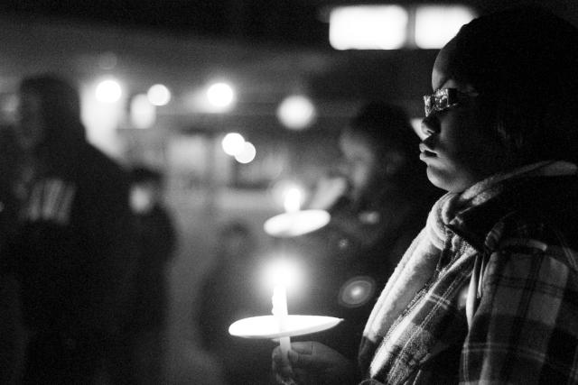 A man stands with a candle during a night time vigil.