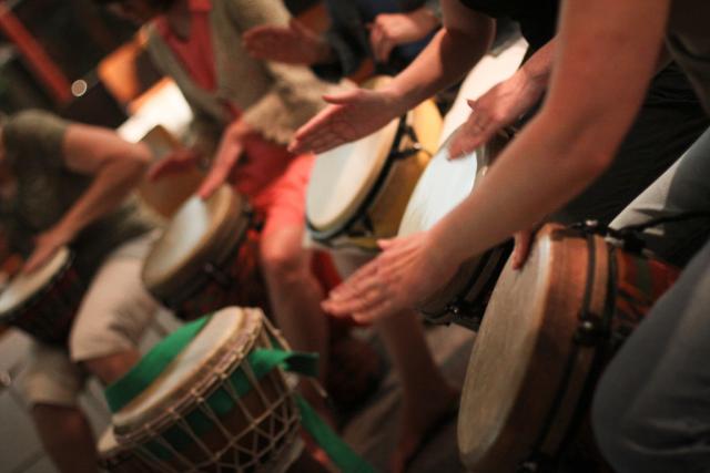 A row of djembe drums being played.