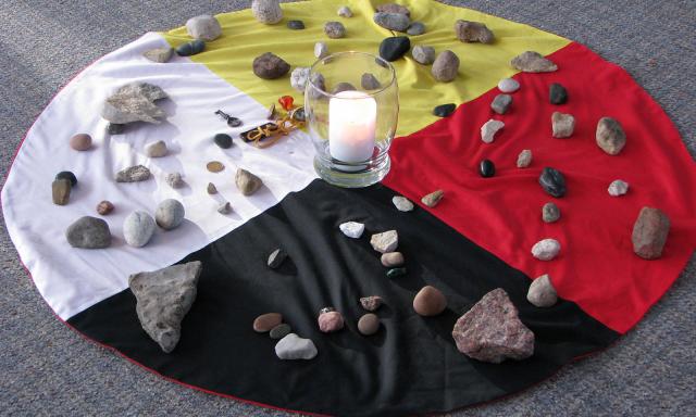 Photo of cloths combined to make an aboriginal medicine wheel with stones placed atop