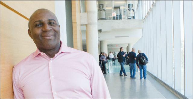 The author, a middle-aged Black man, leans against a wall and smiles.