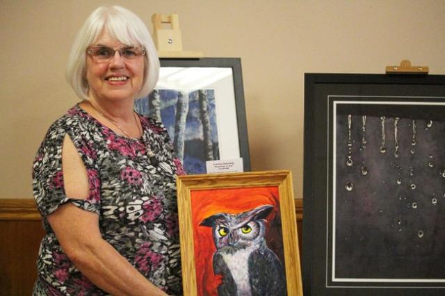 Corrine Donnelly, am artist who lives in the Bradford area, holds up a painting of an owl that was on display in the Bradford Arts Centre.