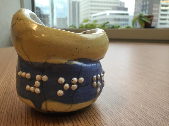 This ceramic raku by Rev. Susan Woodhouse reads "cup of blessings" in Braille. The colours represent discerning the God-given gifts of disability and offering them to God’s people. Ceramic raku