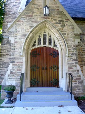 Dark red arch-shaped doors of a stone church.