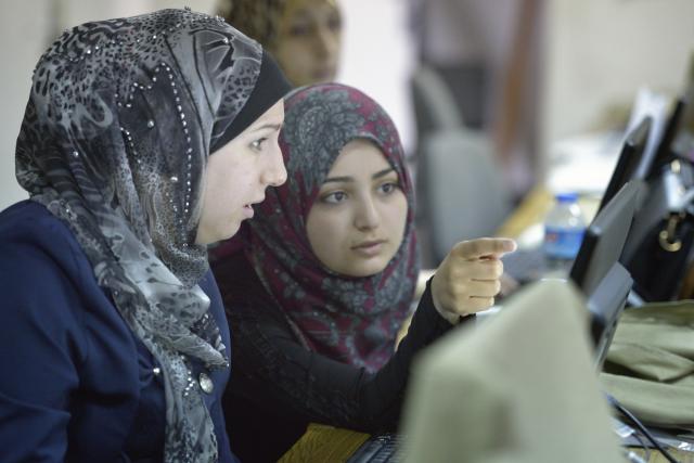 Women in a computer and secretarial skills class in the Vocational Training Center in Gaza City. The center is sponsored by the Department of Service for Palestinian Refugees of the Middle East Council of Churches; DSPR is a member of the ACT Alliance. Close-up of women in discussion in front of a computer screen.