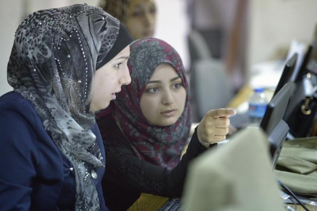 Close-up of women in discussion in front of a computer screen.