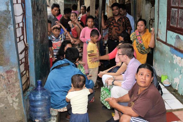 Moderator Jordan Cantwell surrounded by a group of people, including children, while visiting a ministry of the Student Christian Movement in Indonesia.