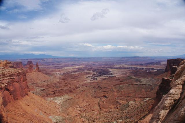 A photo looking down into a vast reddish canyon in the desert of Utah. 