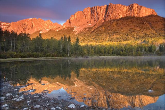 A golden sun shines on Mount John Laurie, known as Yamnuska, in Alberta.