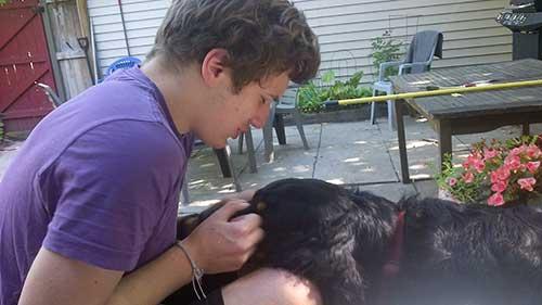 A young man plays with his dog. Time apart is so needed.