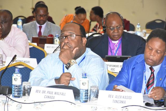 The author, Paul Douglas Walfall, wearing a light blue shirt, listens intently from his desk at the Misleading Theologies Conference, in Kenya, Oct. 2019.jpg