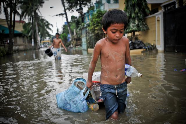 A young boy drags possessions through the flooded streets of Manila, Philippines, in the aftermath of Typhoon Ketsanaon. Boy in the Philippines after Typhoon Ketsanaon
