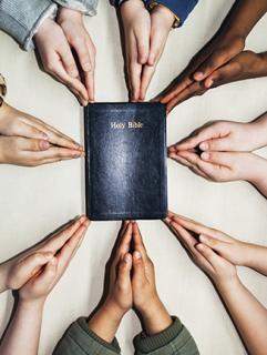 Praying hands around a bible