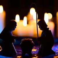 The statues of a Nativity scene are silhouetted by a background of candles.