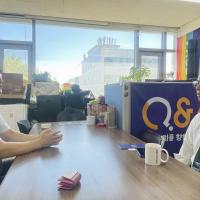 Two men talking together across a boardroom table in an office