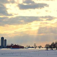 Sunbeams coming through the clouds over an Alberta farm.