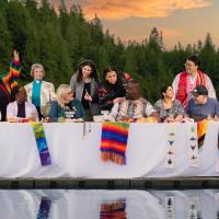 "A Place at the Table" - an iconic image of 12 diverse disciples at a long table, positioned on a dock in a mountain lake.