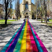A rainbow coloured 100 foot table in front of the historic Metropolitan United Church Toronto