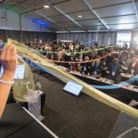 A large room full of people holding ribbons together that reach across the room.