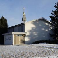 A small white church in front of a snowy lawn.