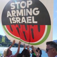 A small group of people holding up a sign that reads "Stop Arming Israel"