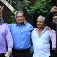 Five Salvadoran men embrace and raise fists in a celebratory gesture