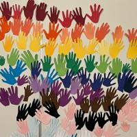 An artwork made of many handprints in rainbows on a wall
