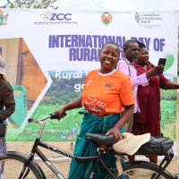 A smiling African woman poses with a bicycle