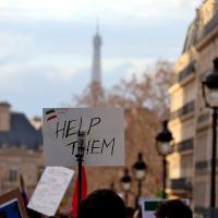 A sign with the words "Help them" is held up at a street protest