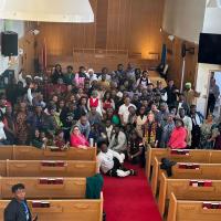 A group photo of a large amount of Africans smiling at the front of a church