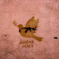 Graffiti on a wall shows a peace dove with a gun over-imposed.