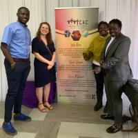 A group of four people smiling in front of a banner with info on CAC