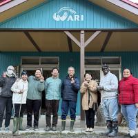 A group of people smiling and holding eggs outside of a farmhouse