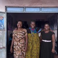 Three African women stand smiling in a doorway