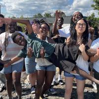 10 youth post for a photo energetically, with one being held across the middle by all