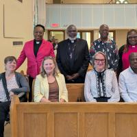 Eight people, five Black and three White, standing and sitting in church pews