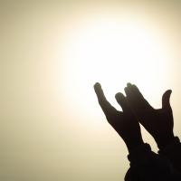 hands lifted in prayer toward light