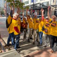 A group of people in yellow shirts in the streets raise their fists